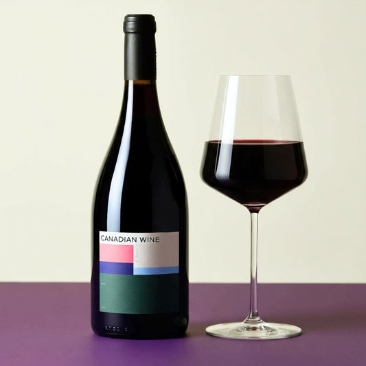 Bottle of Canadian wine for wine subscription with a glass of red wine on a purple surface