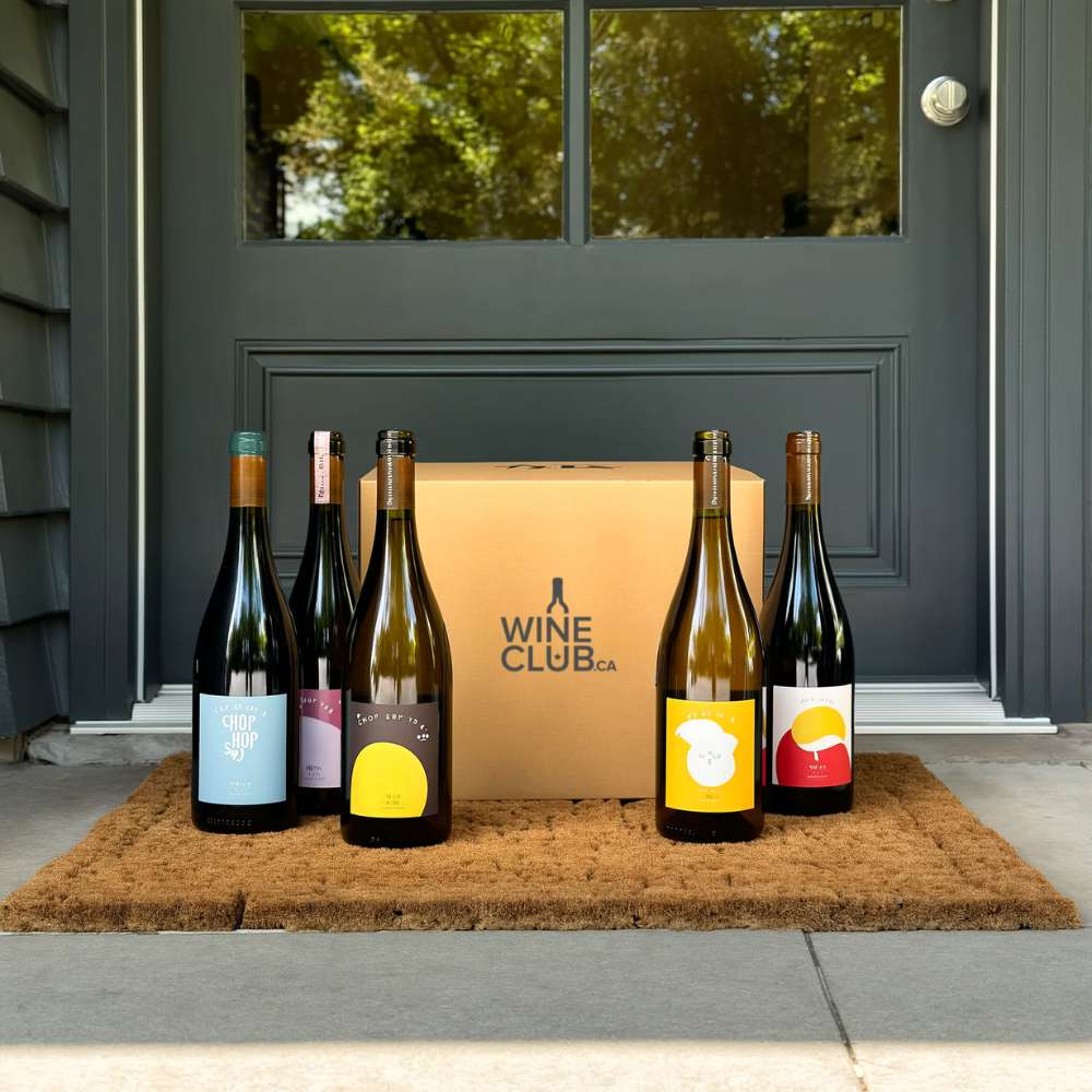 Wine bottles and a box labeled 'Wine Club' on a doormat in front of a door.