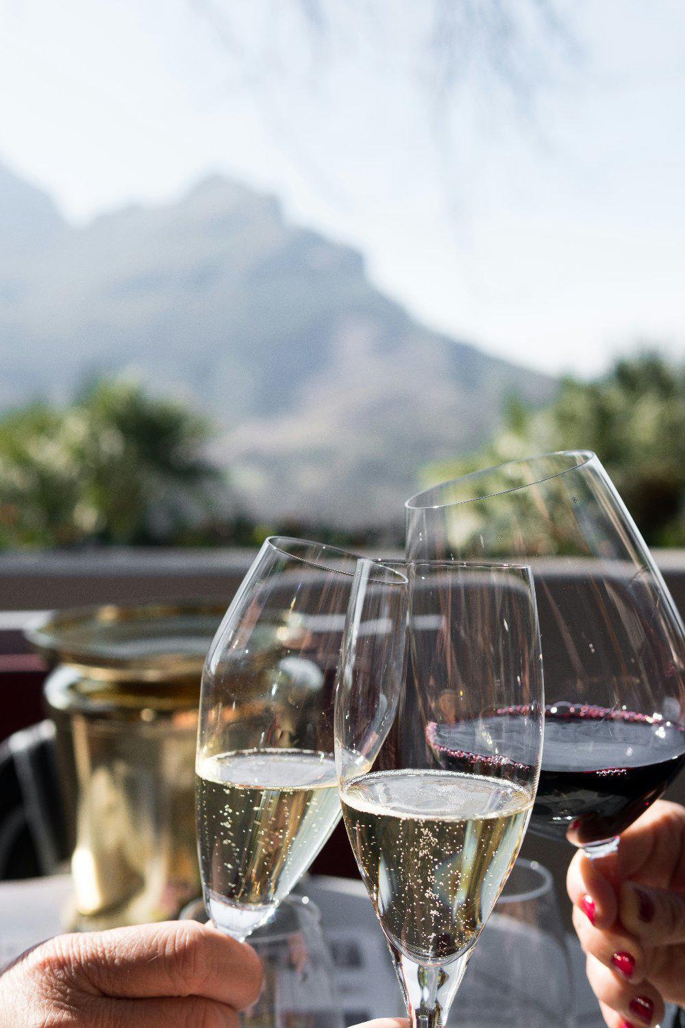 Glasses of red and white wine cheering with mountains background