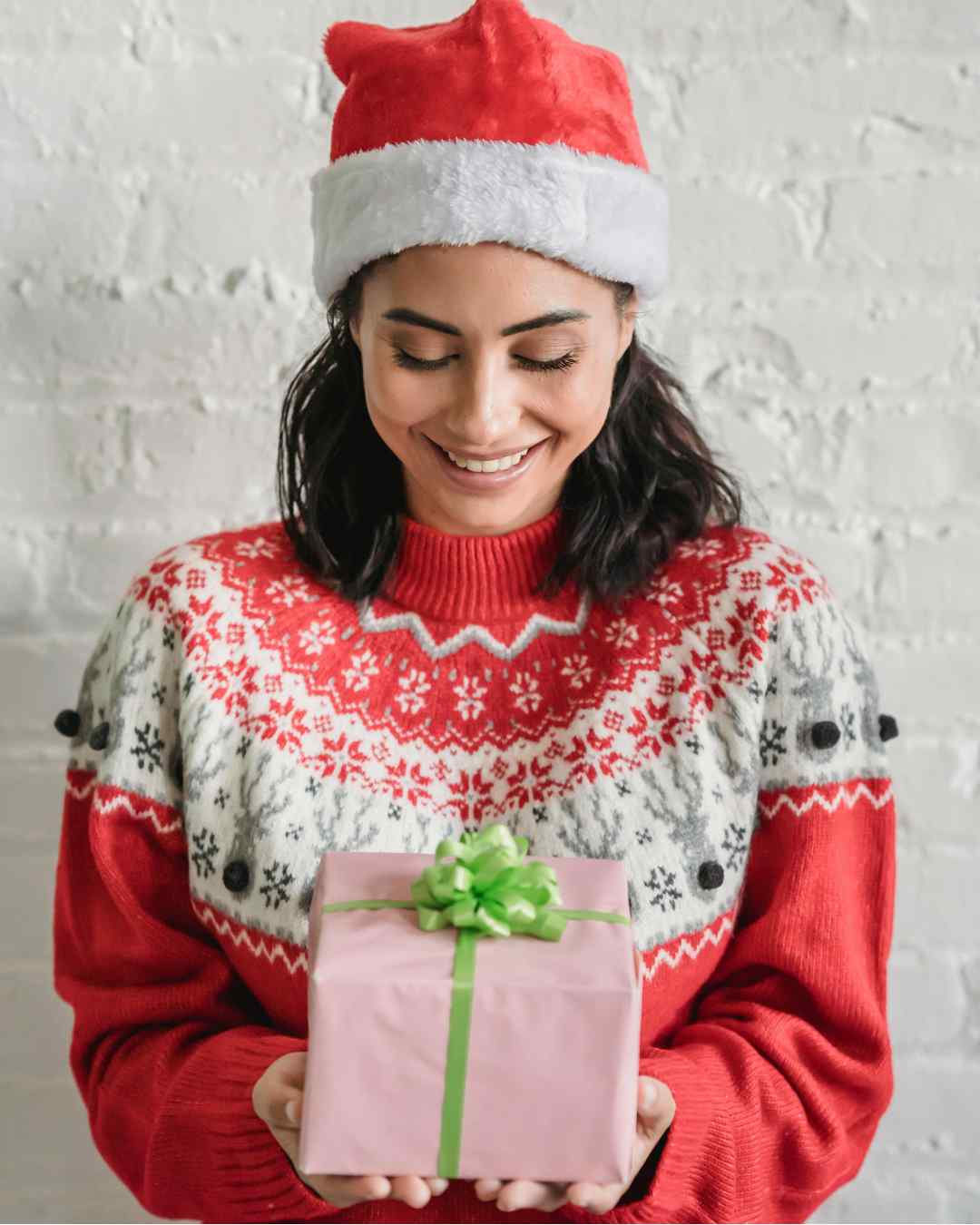 Woman with holiday attire holding a gift box or basket with wrapping containing wine