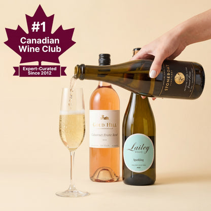 Wine pouring from a bottle into a glass with wine club branding on a beige background