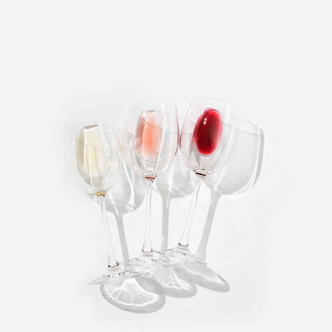 Glasses half empty of red white and rose wine laying in white background