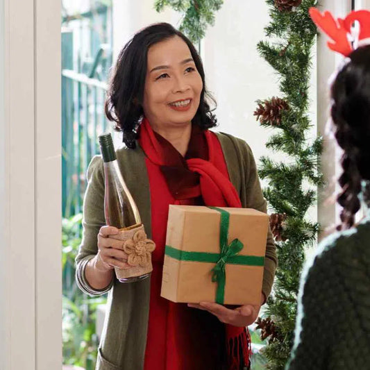 Woman holding a bottle of wine and a box or basket in holiday background