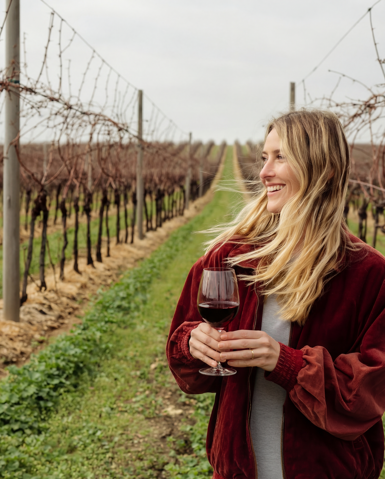 Woman holding a glass of red wine in a vineyard
